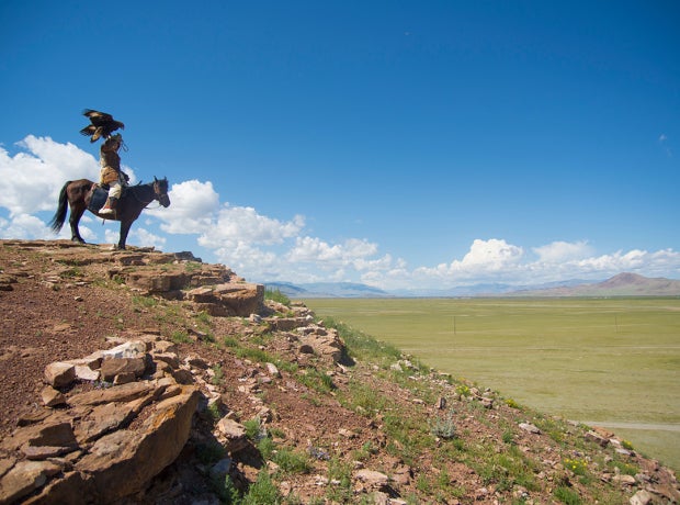 Kazakh eagle hunter on his horse in altai mountains, mongolia
